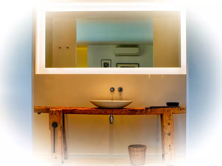 le plan vasque et le miroir d'une salle de bain du gite la cubane ; le plan vasque est un établi ancien transformé pour recevoir la vasque aux lignes simples