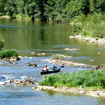 Sur l'aveyron, à proximité de Saint Antonin Noble Val, un kayak au milieu de la rivière avec deux personnes à bord, vues de dos ; le kayak vient de franchir un peit ressaut caillouteux