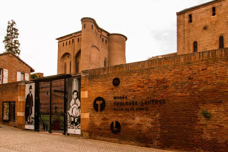 l'entrée du musée toulouse-lautrec à albi ; la grille d'entrée, le mur en briques, dans le fond les bâtiments épiscopaux en brique