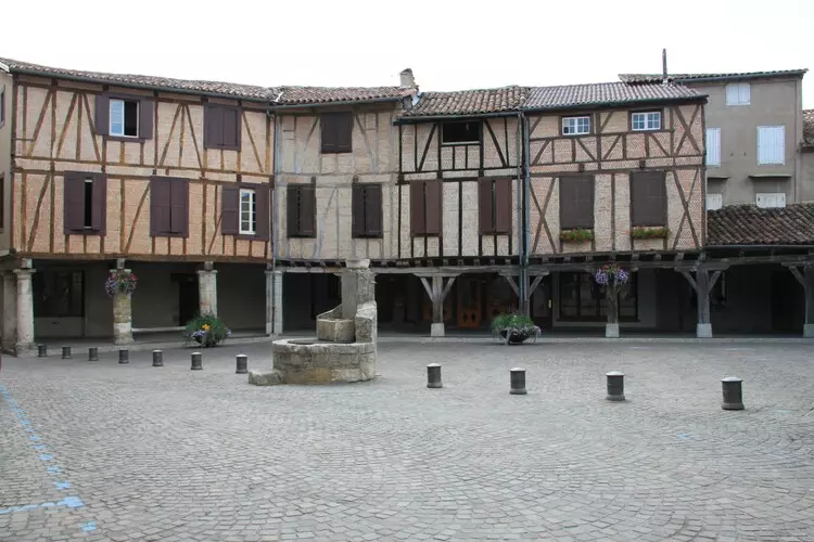 la grand place du village de lautrec (tarn, occitanie), place pavée, maisons en brique et colombage, une fontaine au centre
