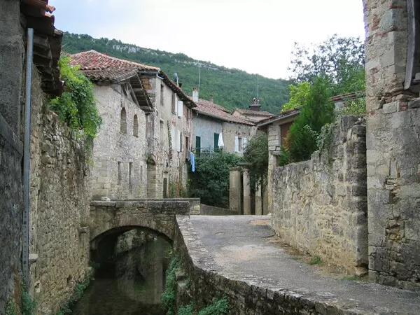 la ruelle du lavoir à saint antonin noble val, village médiéval de tarn et garonne dans la région occitanie ; de part et d'autre, des maisons en pierre et au centre de la photo un petit pont piétonnier qui traverse un ruisseau
