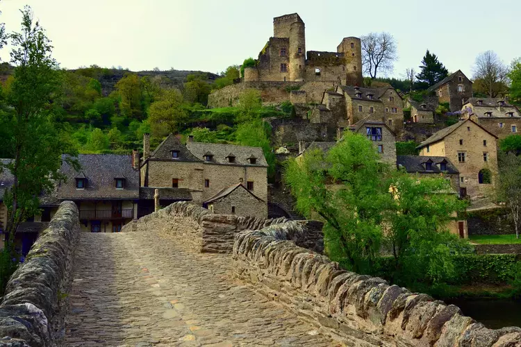 le village de belcastel en aveyron, région occitanie ; le vieux pont qui traverse l'aveyron et au fond le château sur son promontoire