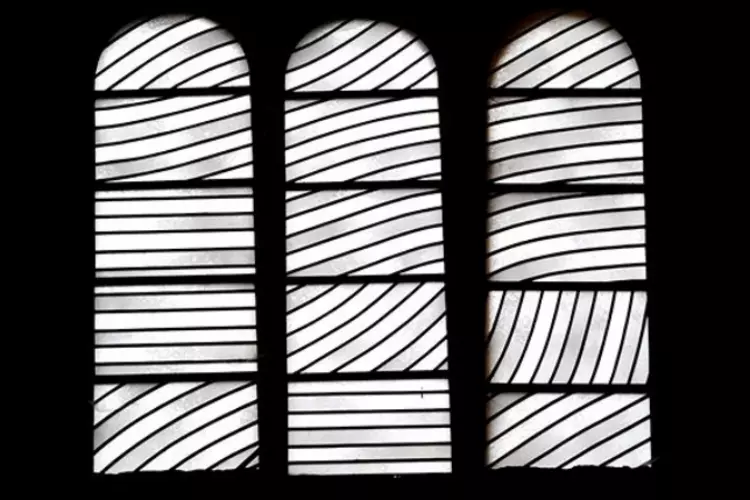 vitrail en trois parties de l'église sainte foy de conques ; les vitraux ont été dessinés par pierre Soulages ; ceux-ci sont en noir et blanc, avec des lignes droites ou courbes