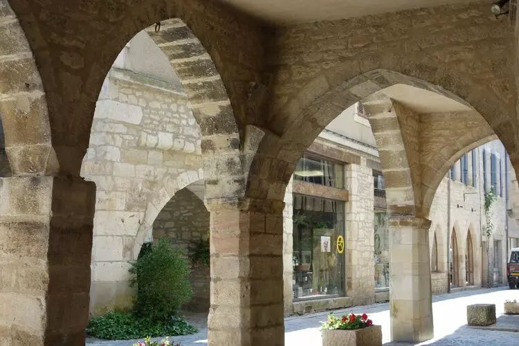 Une rue de villeneuve d'aveyron, bastide à proximité de villefranche de rouergue ; sous les arcades de pierre, on aperçoit la ru
