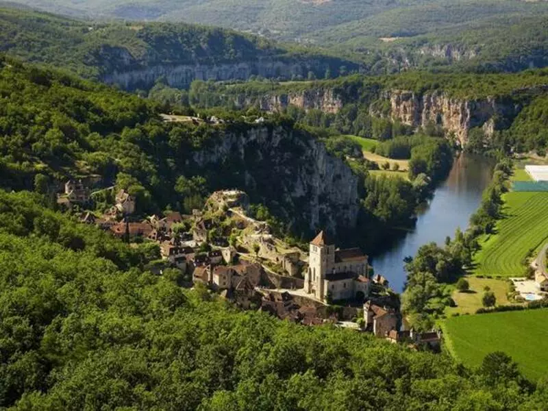 le village de saint-cirq-lapopie dans le lot, région occitanie ; on voit le village perché sur sa falaise, surplombant la rivière lot, avec les gorges du lot au loin