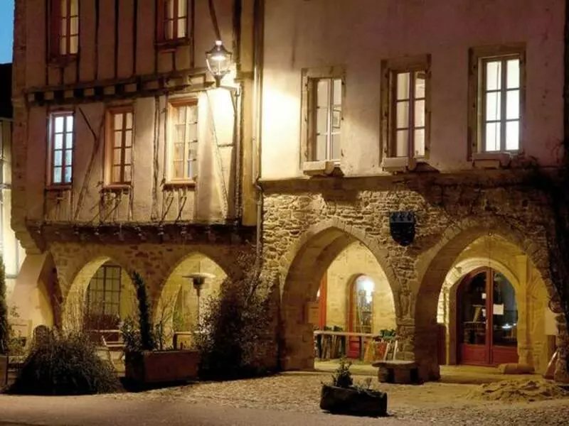 sauveterre de rouergue, village médiéval de l'aveyron dans la région occitanie ; la nuit, les façades de deux maisons sont éclairées, avec au rez de chaussée les arcades typiques de la ville