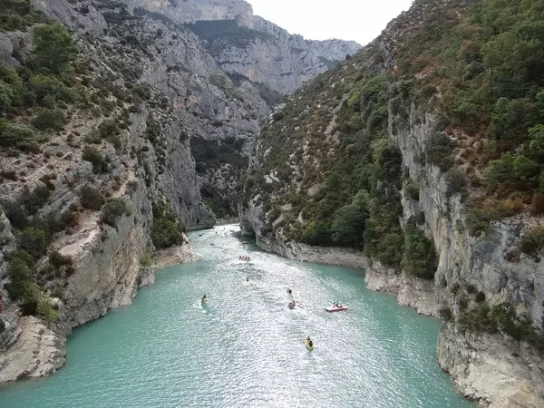 vue plongeante sur les gorges de l'aveyron, très encaissées avec les parois calcaires ; en contrebas, la rivière aveyron, quelques canoës et kayaks qui descendent le cours d'une eau limpide